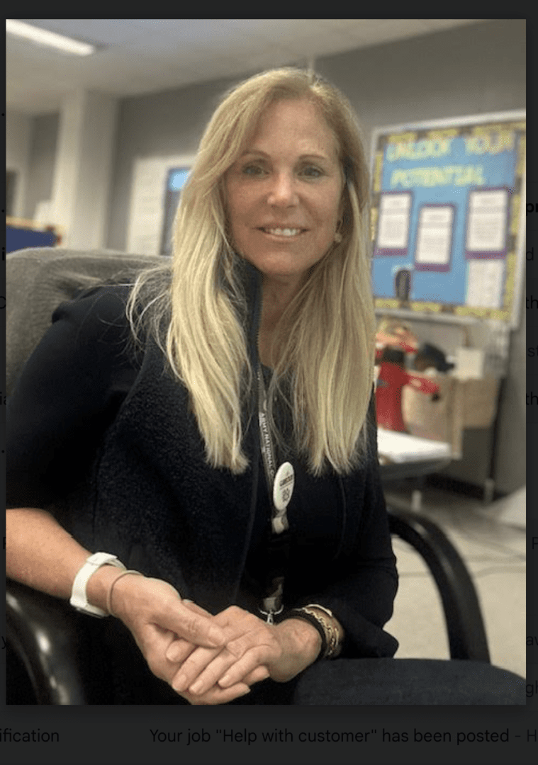 A woman sitting in an office chair wearing a black jacket.